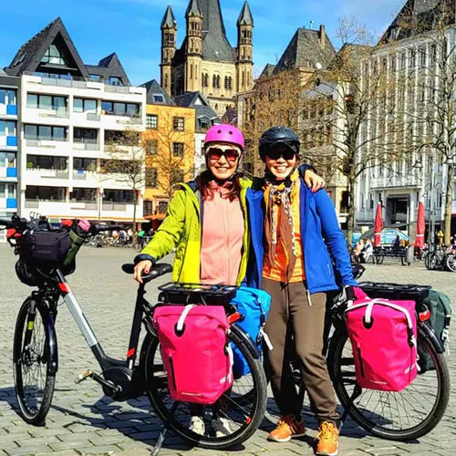 Buntes Foto von E-Bike Fahrradtour Fahrradreise ab Köln von zwei Frauen mit pinken Fahrradtaschen.