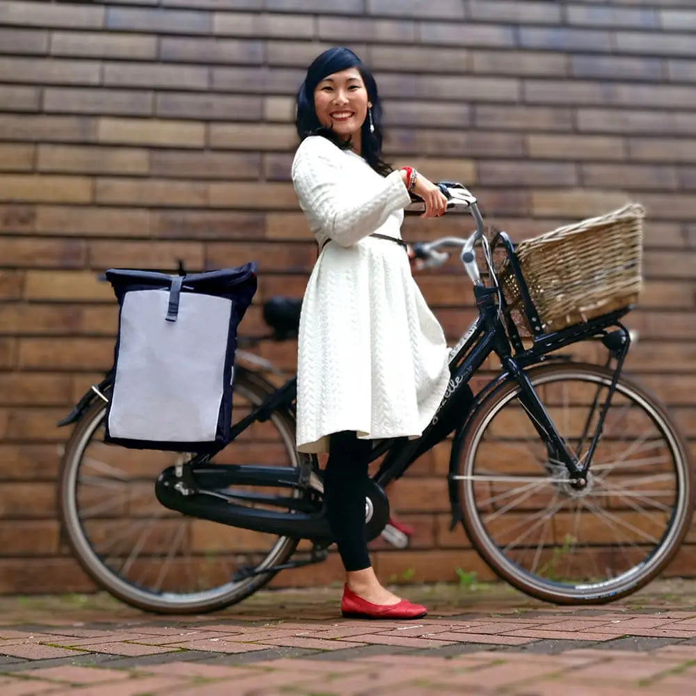Frau auf dem schwarzen Fahrrad mit der schicken Bomence Urban Create reflektierende Fahrradtasche und Rucksack 2-in-1. 