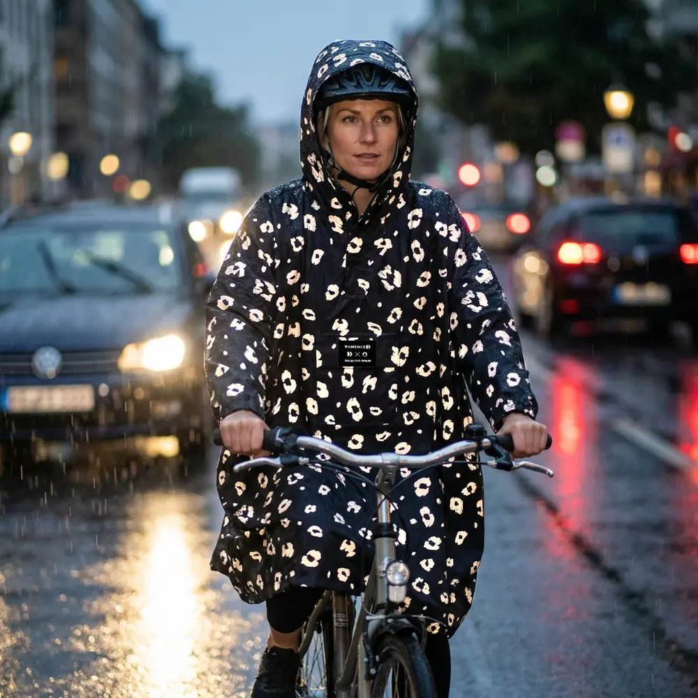 Frau mit sichtbarer Regenbekleidung reflektierend auf dem Fahrrad auf der Straße
