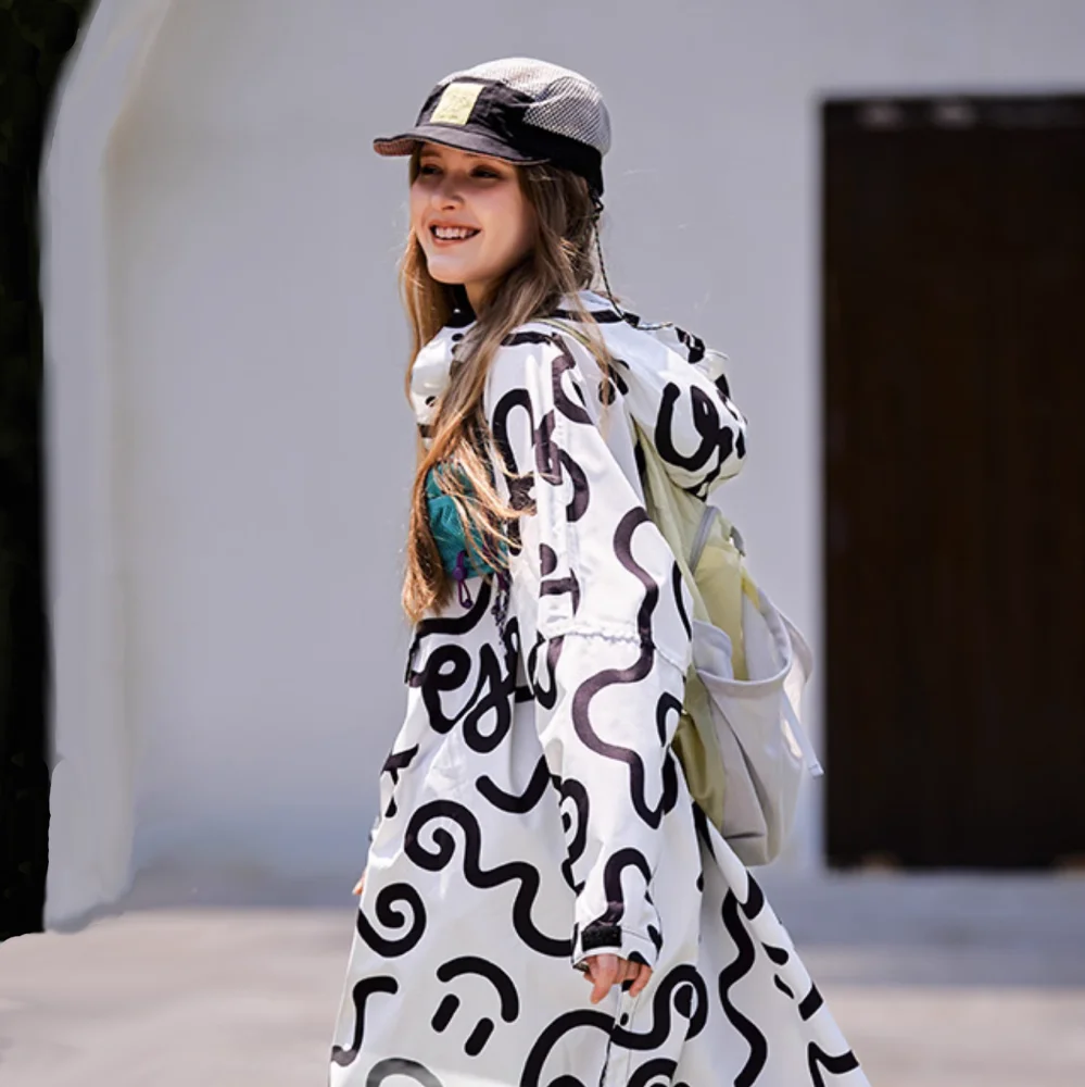 Heller Regenponcho mit Kapuze an junger Frau