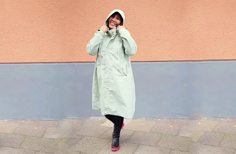 Mintgrüner Regenmantel oversize lang. Video zur Darstellung der Produktdetails. Frau mittleren Alters trägt die Variante mint.